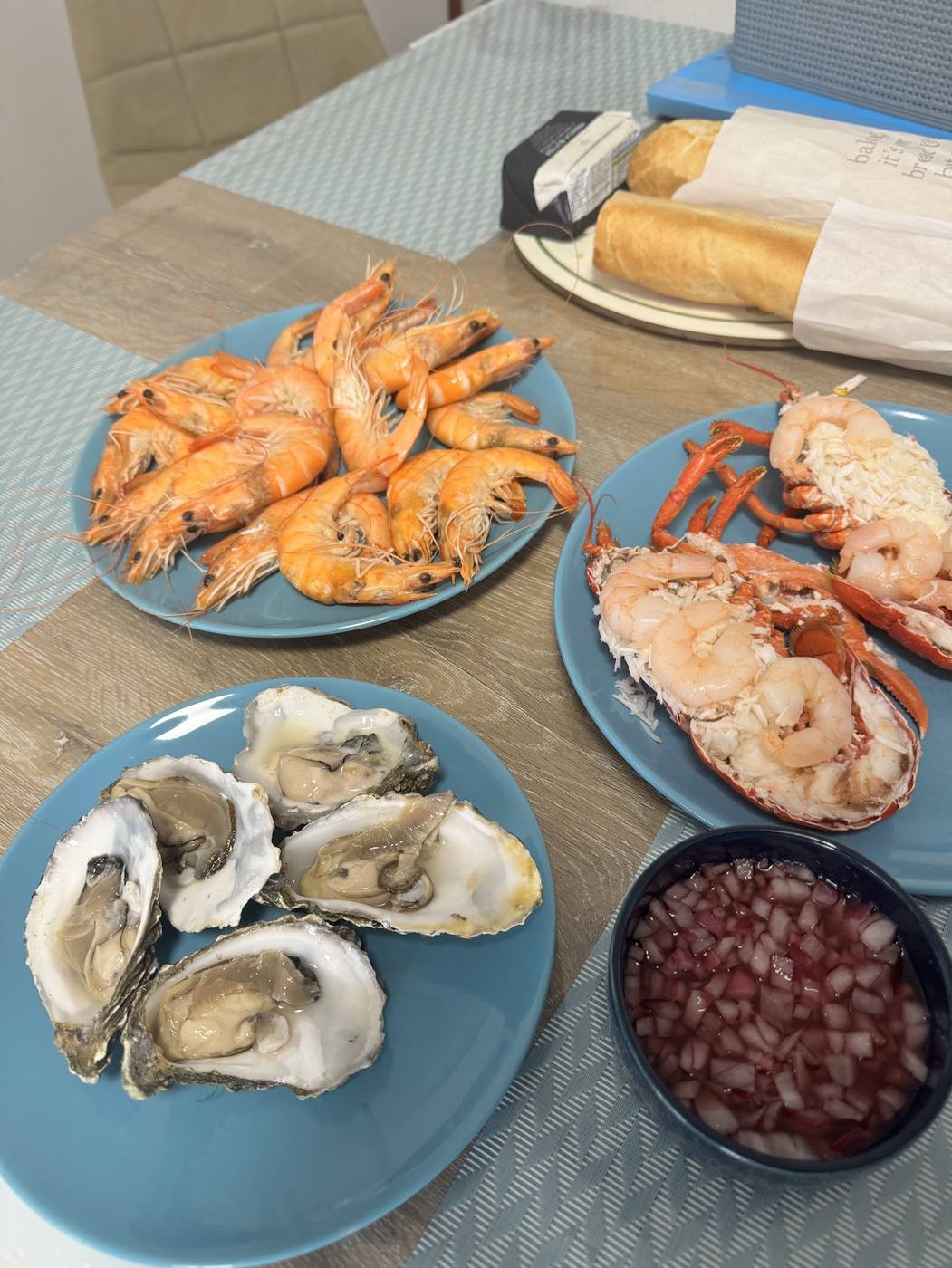 Plates of prawns, langoustines, lobster and oysters with bread on a table, from Berwick Seafood Company.