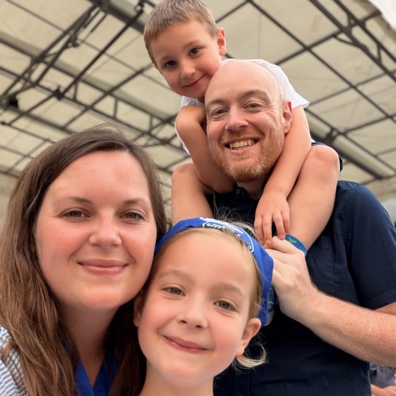 Dan, Julia and their two children, six and seven, smiling together at a summer event.